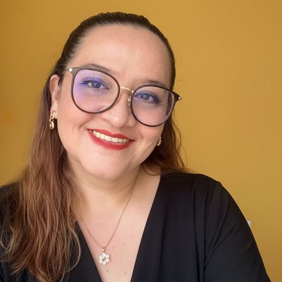 Mujer sonriente con gafas y blusa negra.