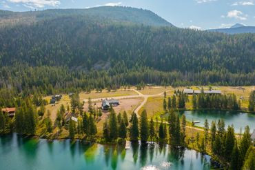 Scenic view of a lakeside village surrounded by forest and mountains.