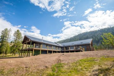 Modern mountain cabin with solar panels under a blue sky.