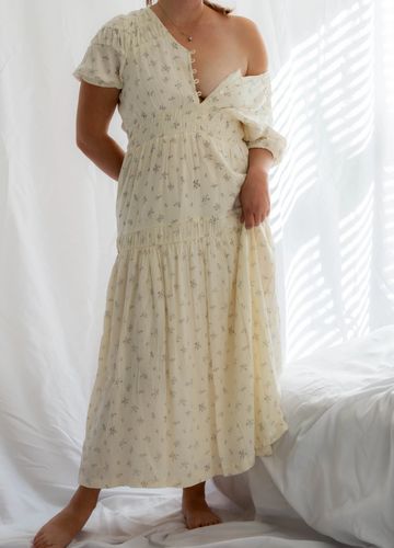 Woman in a beige floral one-shoulder dress.