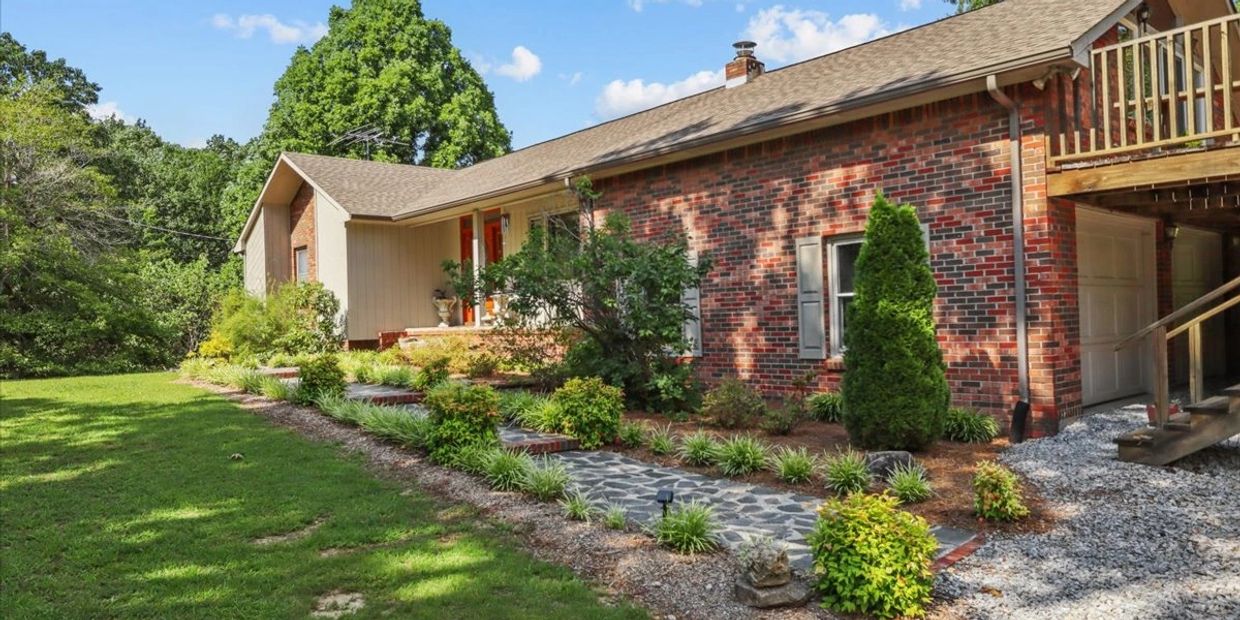 Brick and wood exterior house with landscaped garden and stone pathway.
