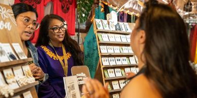Two women at a jewelry stall talking to a customer.