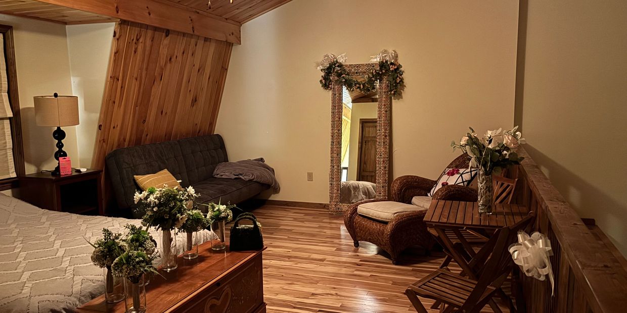 Cozy wooden attic bedroom with floral decorations and comfortable seating.