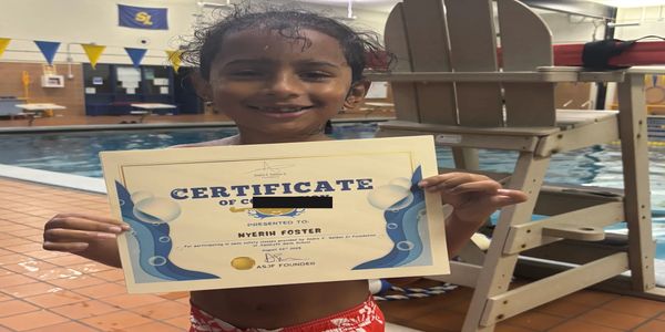 A child happily holding a swimming certificate by the poolside.