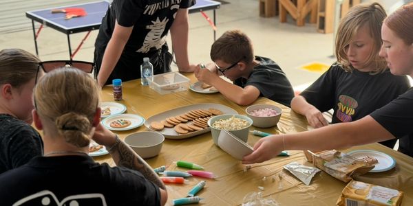 Kids and adults making snacks together at a table.
