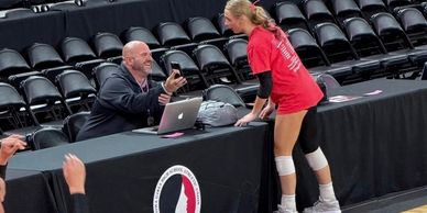 Man showing phone to a female athlete at a sports event.