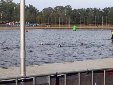 Swimmers in wetsuits participating in an open water race in a lake.