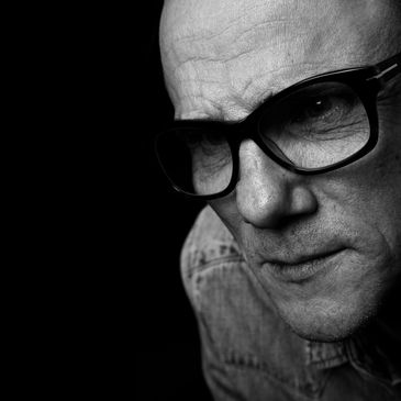 Close-up black and white portrait of a serious man wearing glasses.