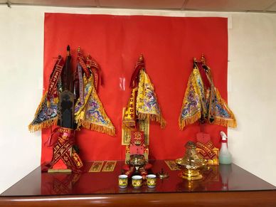 Traditional Chinese altar setup with embroidered flags and ceremonial items.