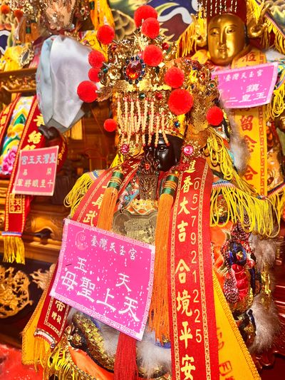 Intricately decorated Chinese deity statue adorned with red and gold ornaments.