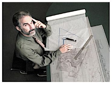 Architect or engineer working on technical drawings at a desk.