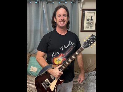 Man holding an electric guitar and smiling.