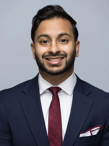 Young man in a suit smiling at the camera.