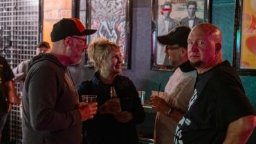 Four people chatting in a dimly lit bar or pub.