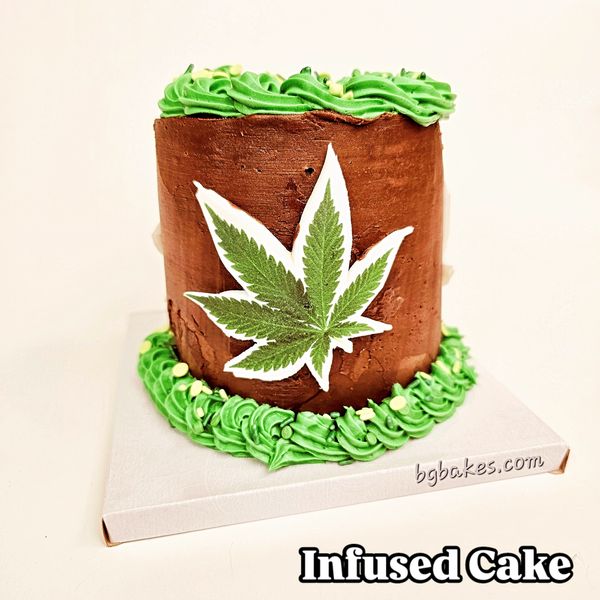 Chocolate cake with green frosting and a cannabis leaf decoration.