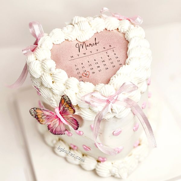 Heart-shaped cake with March calendar and butterfly decoration.