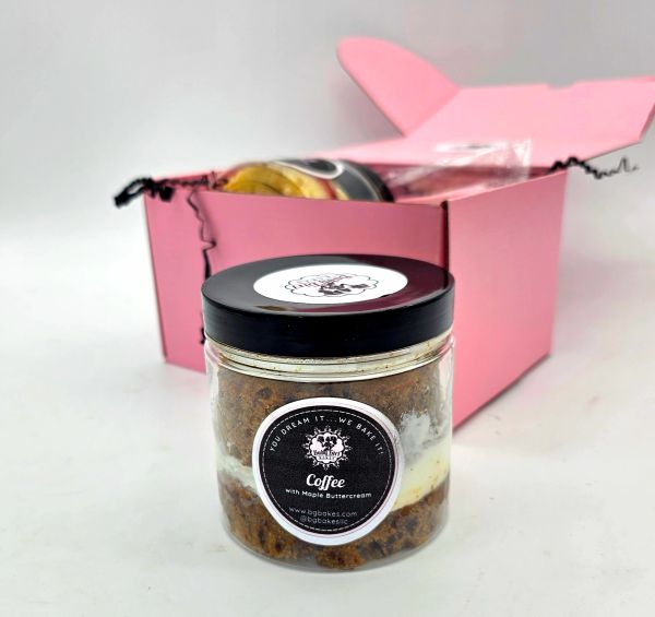 A coffee cake jar with maple buttercream in front of a pink gift box.