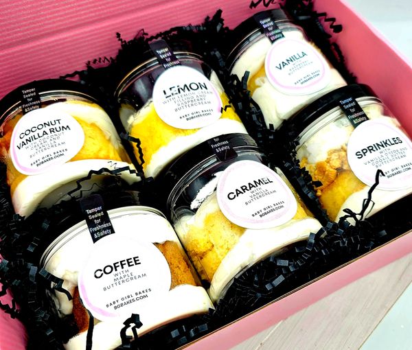A box of assorted cupcake jars with various flavors and buttercream.