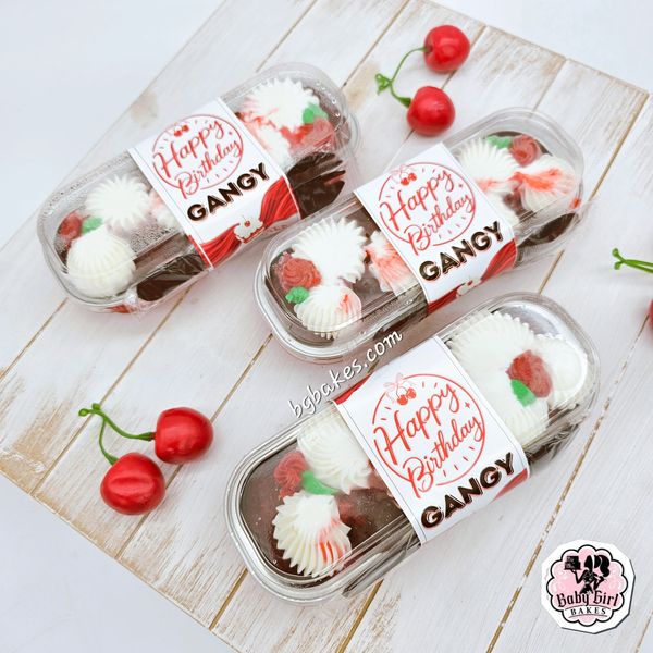 Packaged chocolate birthday cakes with white and red frosting and cherries.
