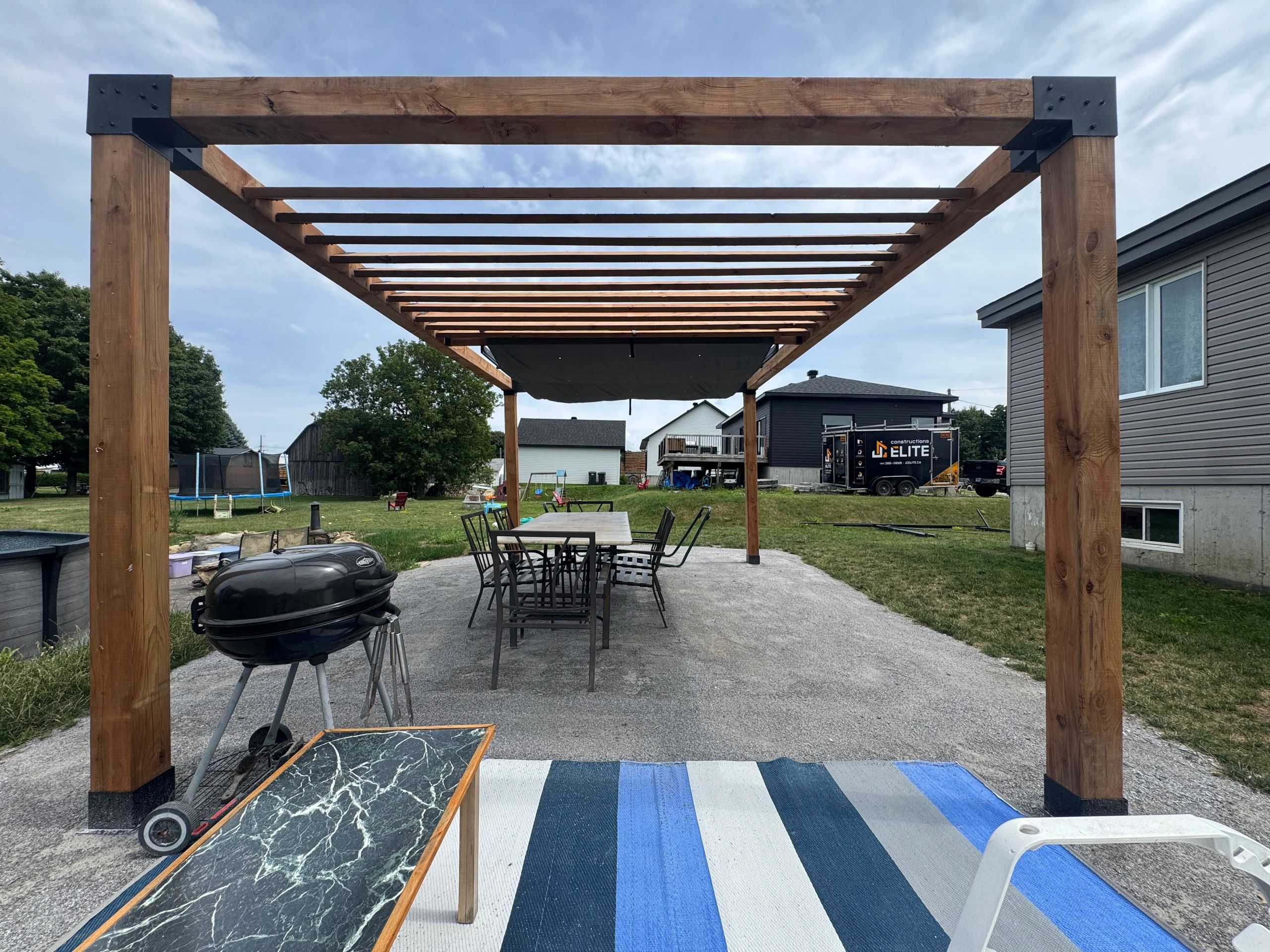 Pergola en bois avec mobilier de jardin et barbecue.