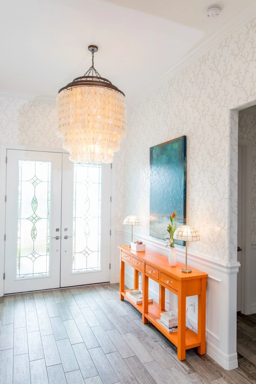 island chic foyer with coral wallpaper. Hermes orange credenza shell chandelier