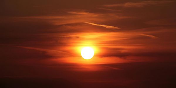 A bright sun setting with orange and red hues in the sky.