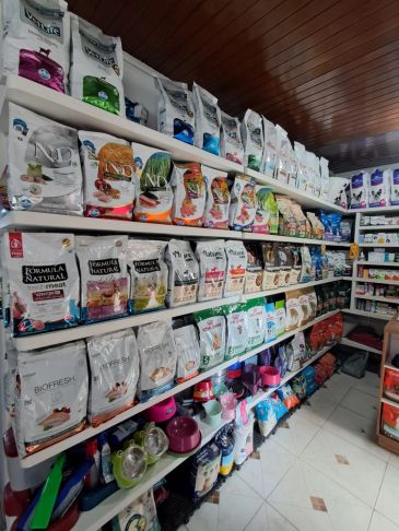 Prateleiras cheias de pacotes de ração e suprimentos para pets.