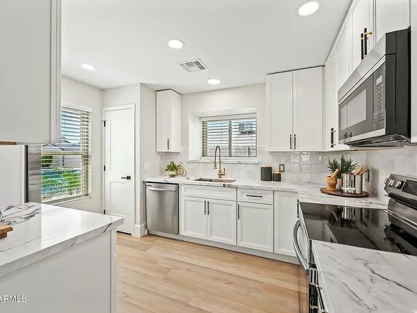 Bright modern kitchen with white cabinets and marble countertops.