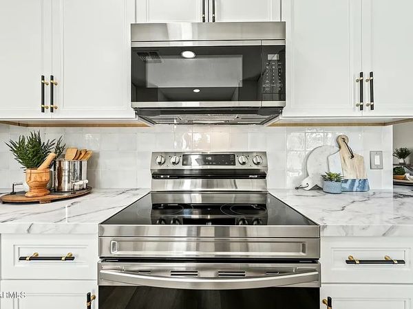 Modern kitchen stove with stainless steel microwave and white marble countertops.