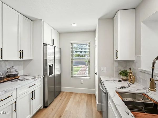Bright modern kitchen with white cabinets and marble countertops.