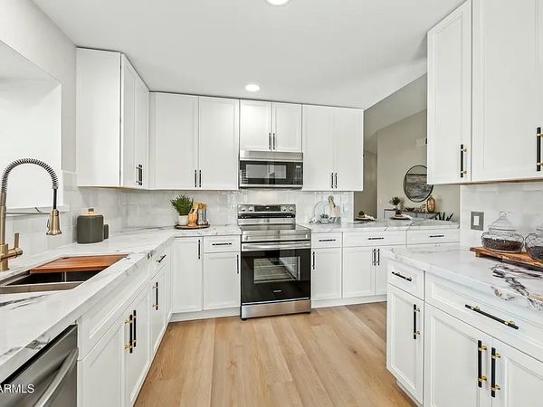 Bright modern kitchen with white cabinets and stainless steel appliances.