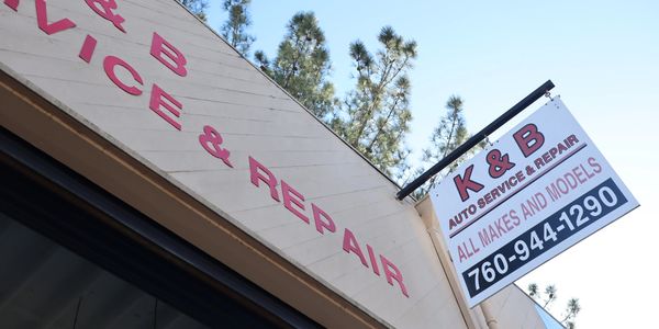 Car shop signage that reads, "all makes and models" and includes phone number, "760-944-1290"
