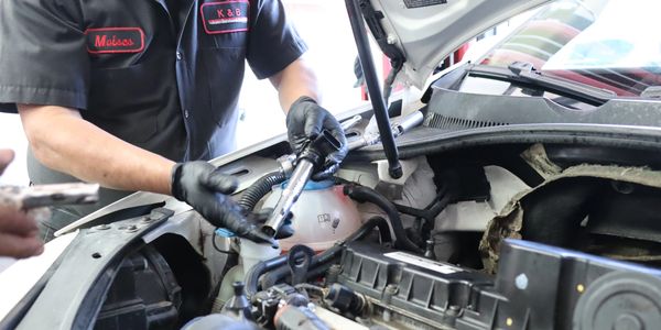 Head mechanic holding tool over the open car hood to build trust with the customer. Encinitas. 