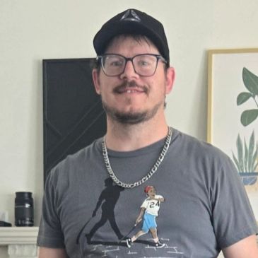 Man wearing glasses and a cap indoors.