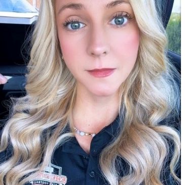 Blonde woman with blue eyes wearing a black shirt.