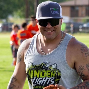 Smiling man in sunglasses and tank top outdoors.