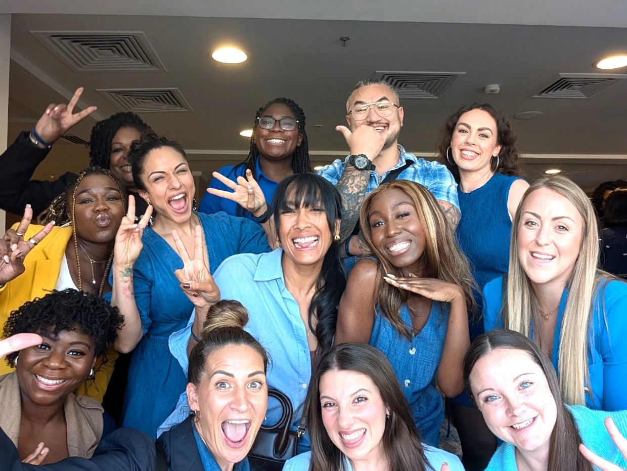 A smiling group of people, all business partners, at a plannet Marketing event, most wearing blue