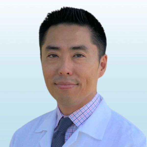 Smiling male doctor wearing a white coat and tie.