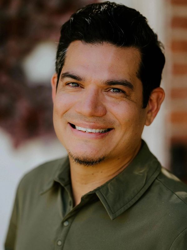 Smiling man in a green shirt with a cheerful expression.
