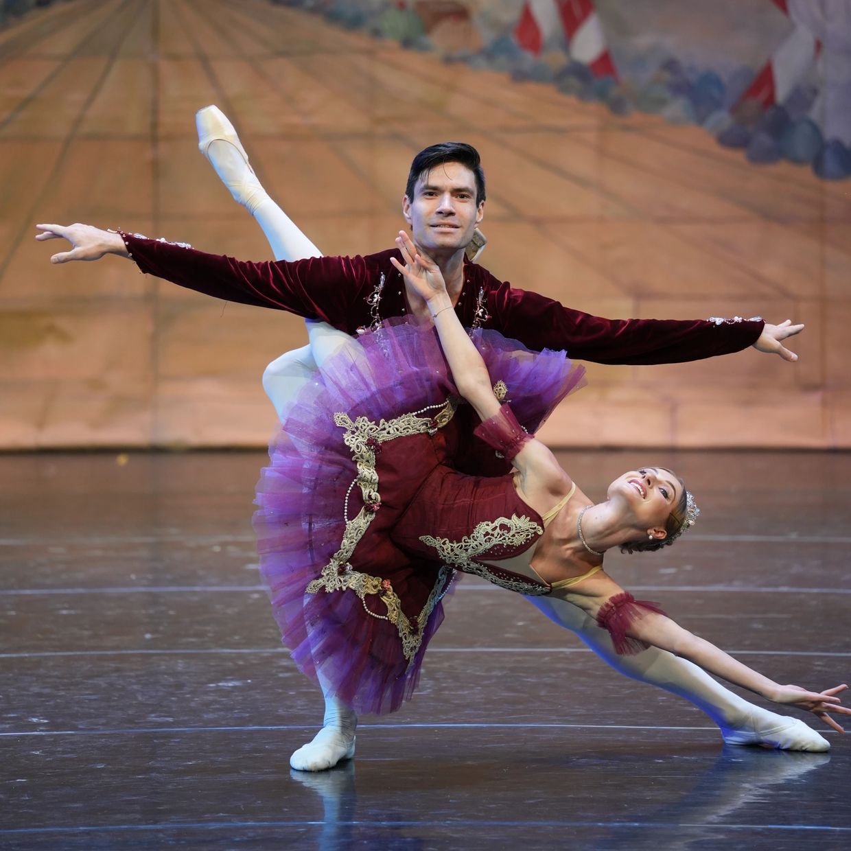 Ballet dancers performing an elegant duet on stage with colorful costumes.