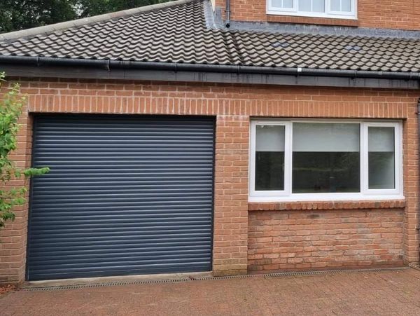 Brick house with a closed black garage door and white window.