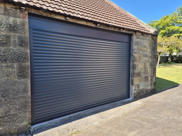 Closed grey metal garage door on stone building.