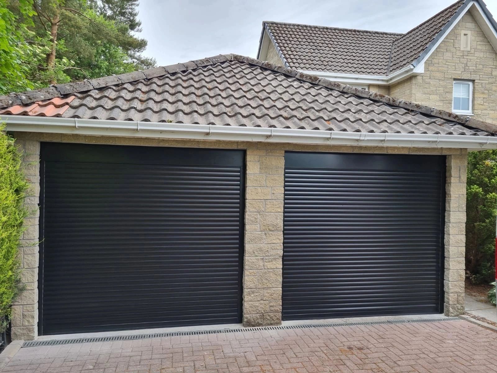 Double black electric roller garage doors on a standalone garage