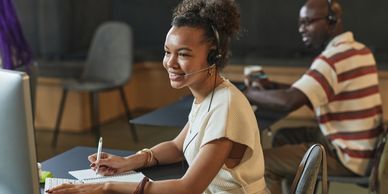 Young Black woman with headset facing computer