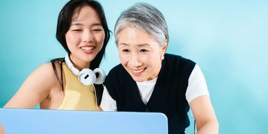 Older Asian woman showing something on the computer to a younger Asian woman