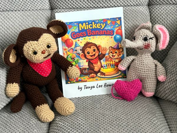 Crocheted monkey and elephant toys with a children's book on a textured gray surface.