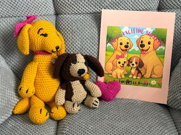Two crocheted dogs with a book featuring cartoon dogs.