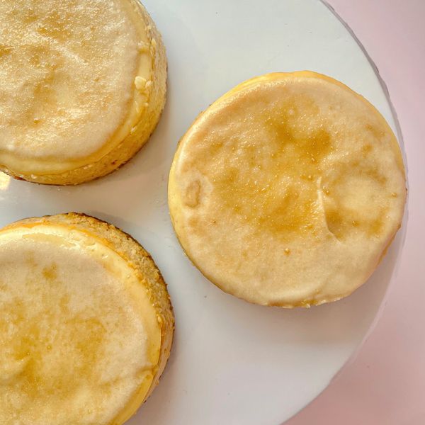 Three golden English muffins on a white plate.