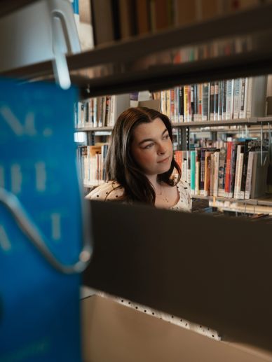 A woman thoughtfully browsing books in a library.