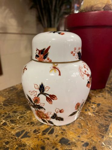 White ceramic jar with floral designs in red, black, and gold.